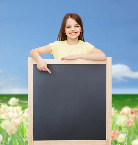 Szczęśliwy mała dziewczynka palcem wskazującym do tablicy — Zdjęcie stockowe