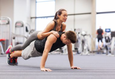 smiling couple doing push-ups in the gym clipart