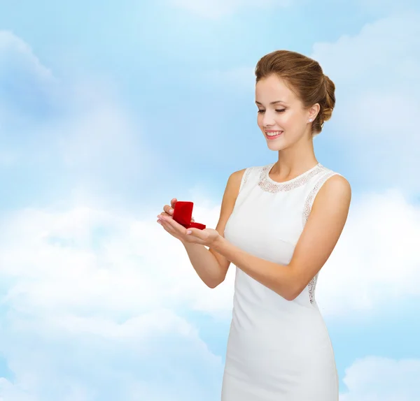 Mulher sorridente segurando caixa de presente vermelho com anel — Fotografia de Stock
