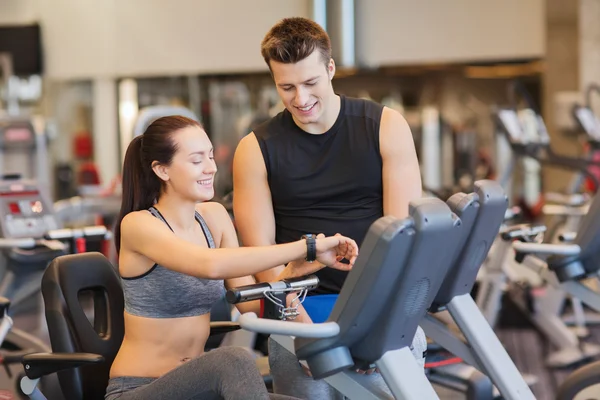 Spor salonunda egzersiz bisikleti üzerinde eğitmen ile mutlu kadın — Stok fotoğraf