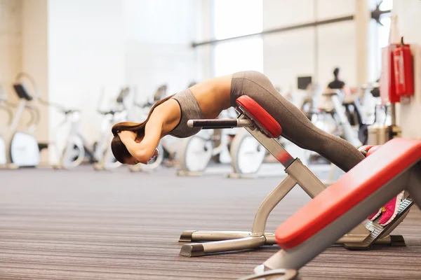 Junge Frau lässt Rückenmuskeln auf Bank im Fitnessstudio spielen — Stockfoto