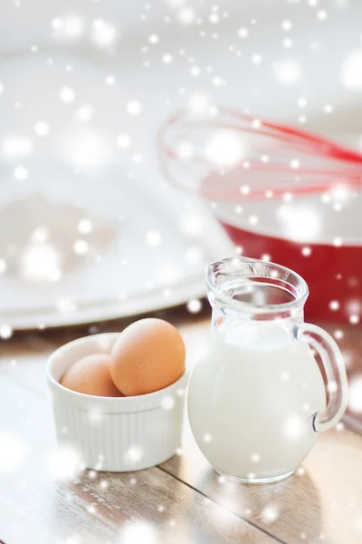 Close up of milk jug, eggs, whisk and flour — Stock Photo, Image