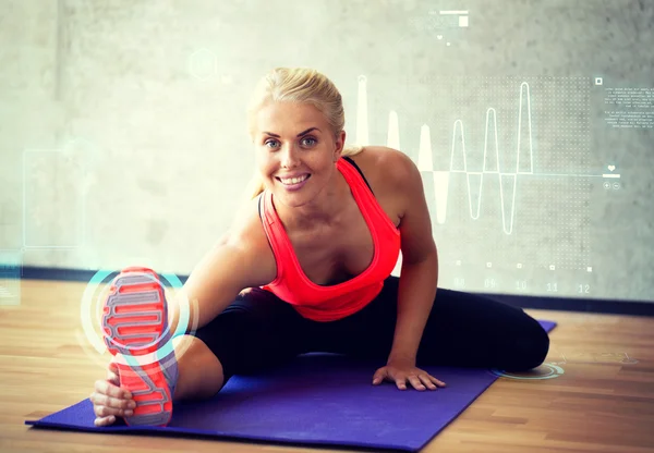 Lachende vrouw doen oefeningen op mat in gym — Stockfoto