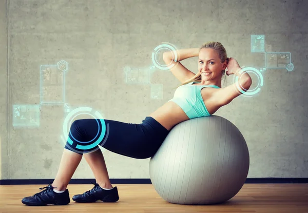 Улыбающаяся женщина с мячом для упражнений в тренажерном зале — стоковое фото