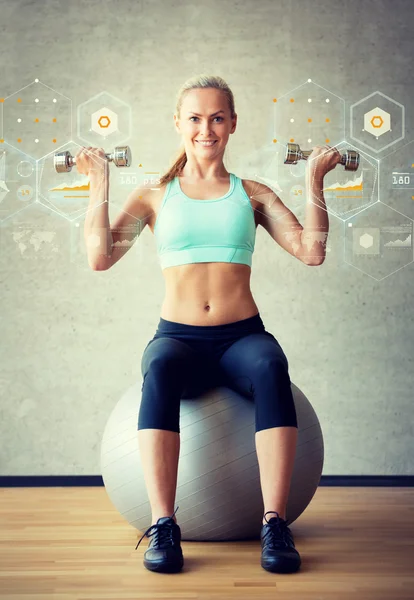 Mulher sorridente com halteres e bola de exercício — Fotografia de Stock