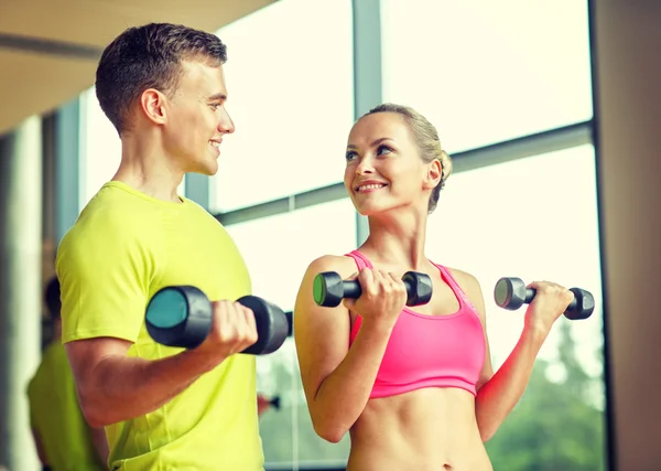 Homme et femme souriants avec haltères dans la salle de gym — Photo