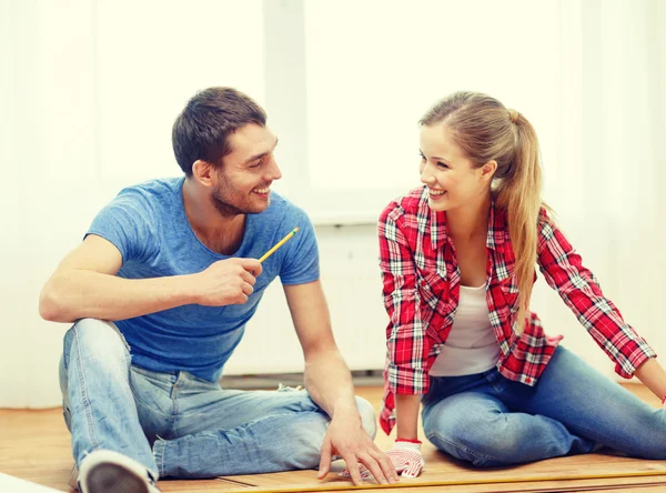 Pareja sonriente midiendo pisos de madera —  Fotos de Stock