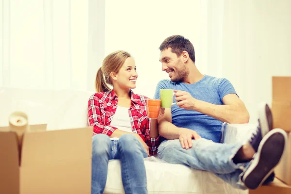 Coppia sorridente che si rilassa sul divano in nuova casa — Foto Stock