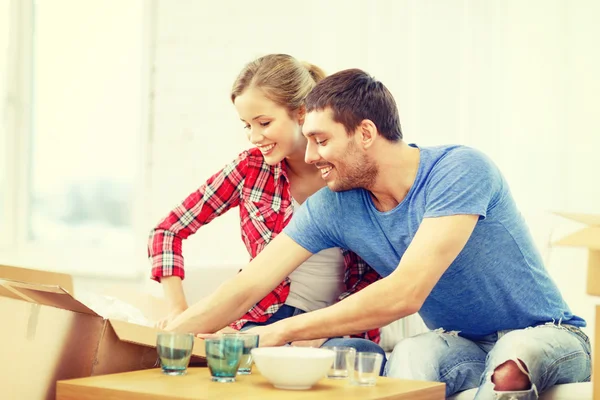 Pareja sonriente desempacando ropa de cocina —  Fotos de Stock