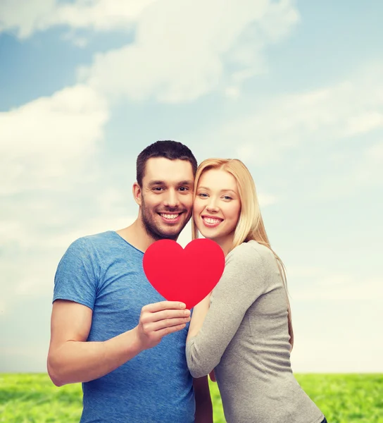 Couple souriant tenant grand coeur rouge — Photo