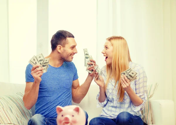 Casal com dinheiro e mesa de ot piggybank em casa — Fotografia de Stock