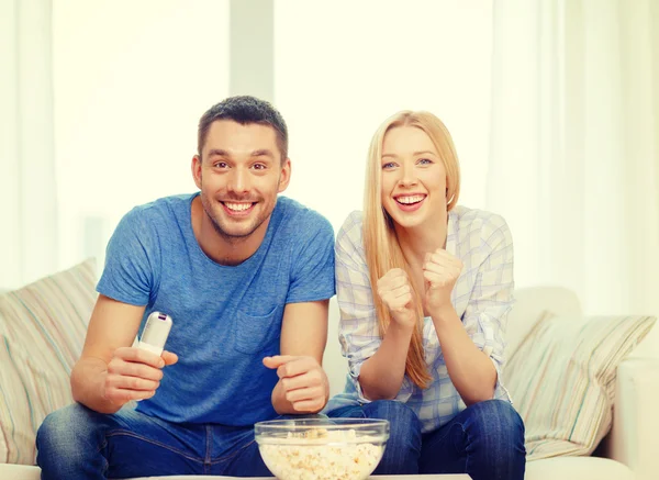Smiling couple with popcorn cheering sports team — Stock Photo, Image