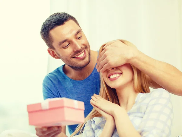 Lächelnder Mann überrascht Freundin mit Geschenk — Stockfoto