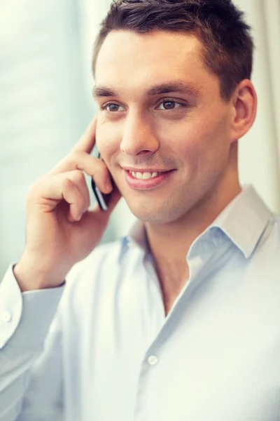 Uomo d'affari sorridente con smartphone in ufficio — Foto Stock