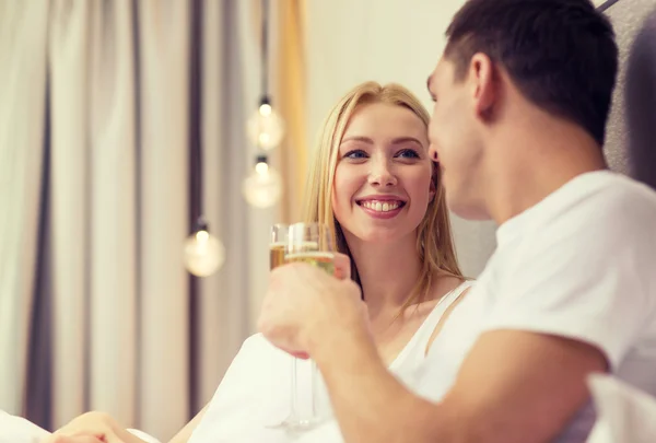 Casal sorridente com taças de champanhe na cama — Fotografia de Stock