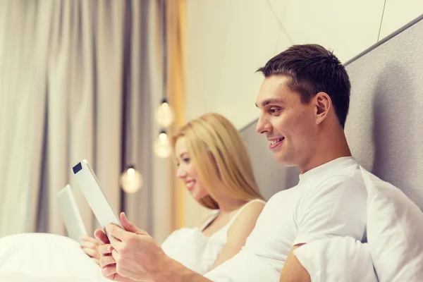 Pareja sonriente en la cama con tabletas PC —  Fotos de Stock