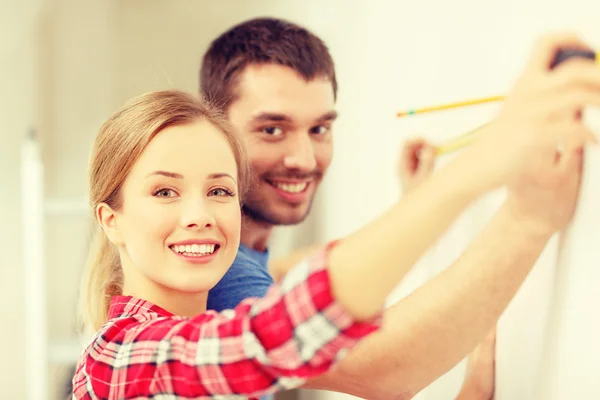 Sorrindo parede de medição casal — Fotografia de Stock