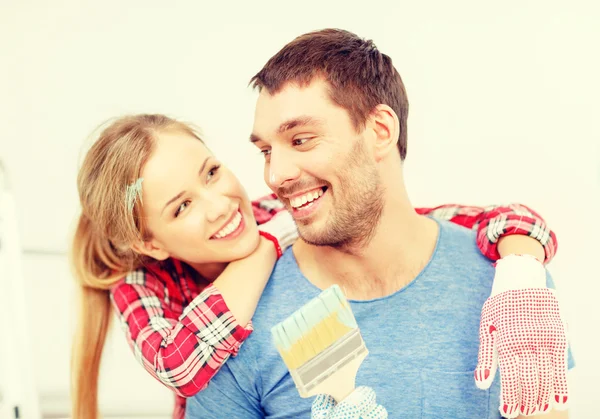 Smiling couple covered with paint with paint brush — Stock Photo, Image