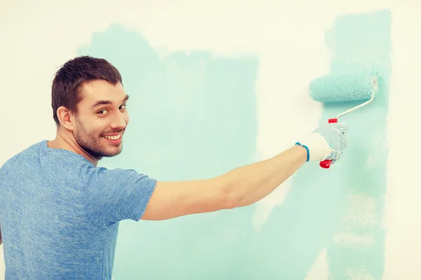 Uomo sorridente pittura muro a casa — Foto Stock