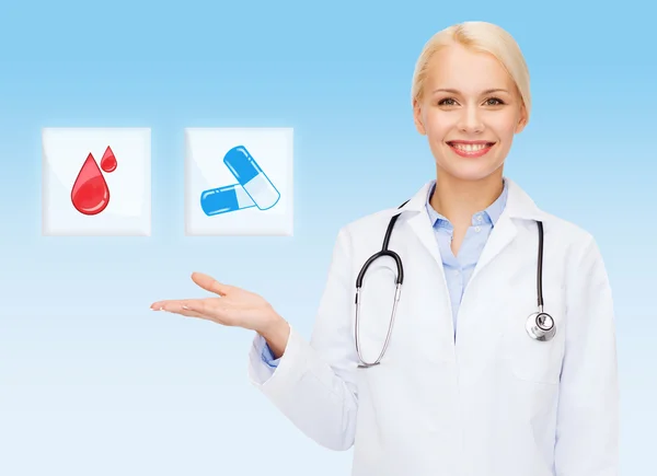 Smiling doctor or nurse pointing to pills icon — Stock Photo, Image