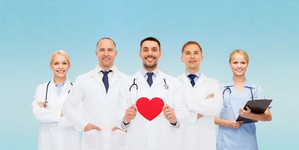 Группа улыбающихся врачей с красной формой сердца — стоковое фото