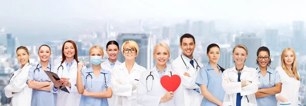 Усміхнені лікарі і медсестри з червоним серцем — стокове фото