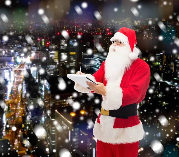 Человек в костюме Санта-Клауса с блокнотом — стоковое фото
