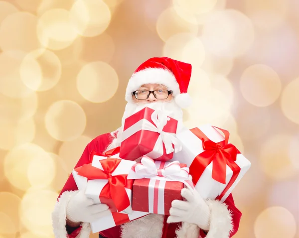 Homem em traje de santa claus com caixas de presente — Fotografia de Stock