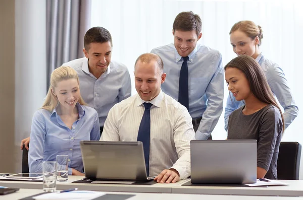 Uomini d'affari sorridenti con computer portatili in ufficio — Foto Stock