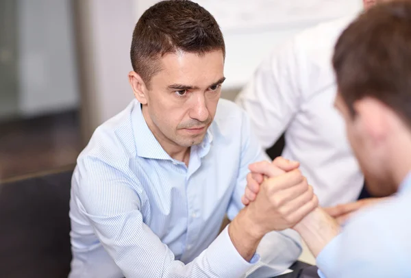 businessmen arm wrestling in office