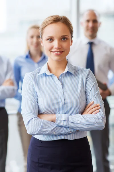 Smiling businesswoman with colleagues in office — Stock Photo, Image