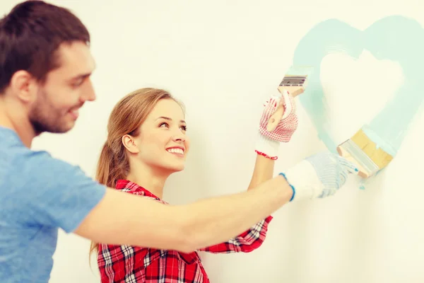 Smiling couple painting small heart on wall — Stock Photo, Image