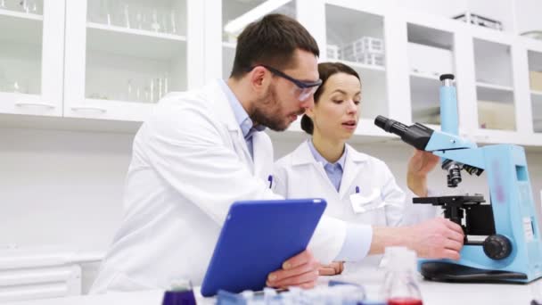 Cientistas com tablet pc e microscópio em laboratório — Vídeo de Stock