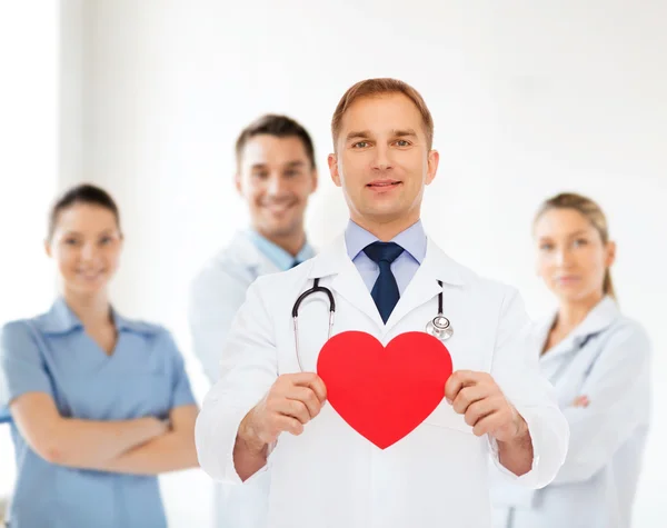 Medico maschio sorridente con cuore rosso e stetoscopio — Foto Stock
