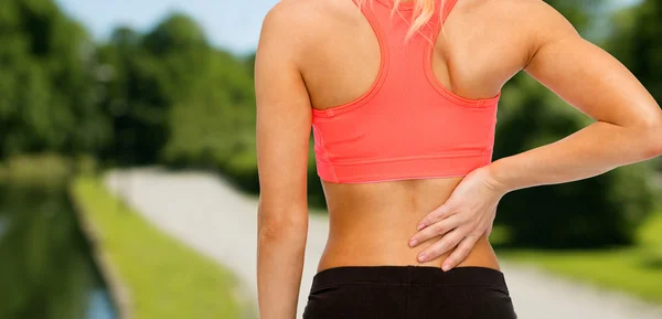 Close up of sporty woman touching her back — Stock Photo, Image