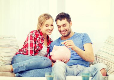 smiling couple with piggybank sitting on sofa clipart