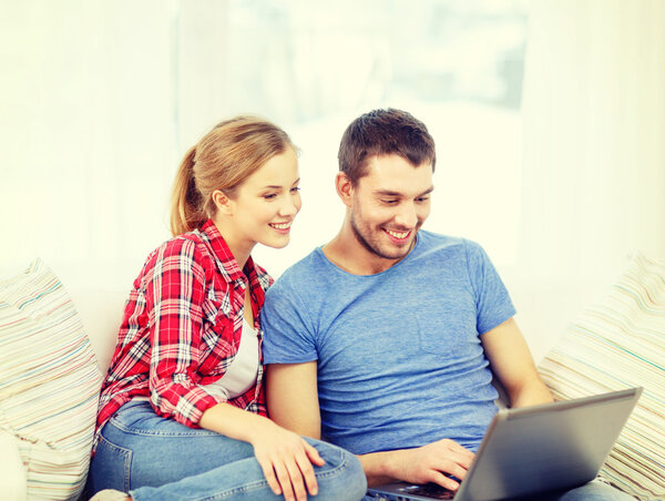 Pareja sonriente con ordenador portátil en casa — Foto de Stock