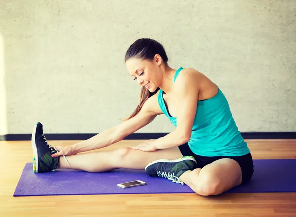 Spor salonunda mat gülümseyen kadın germe bacak — Stok fotoğraf