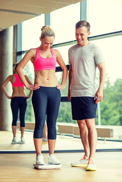 Smiling man and woman with scales in gym — Stock Photo, Image