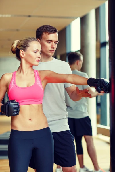 Mujer sonriente con entrenador personal boxeo en el gimnasio — Foto de Stock