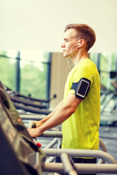 Man met smartphone uitoefenen op loopband in de sportschool — Stockfoto