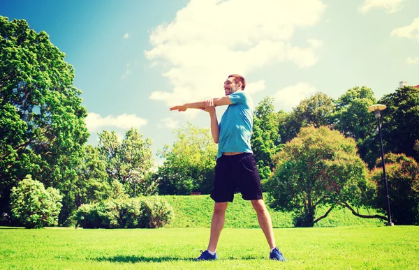 Smiling man stretching outdoors — Stock Photo, Image