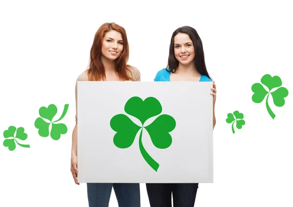 Lachende tienermeisjes houden bord met shamrock — Stockfoto