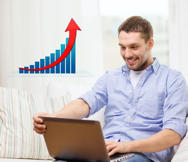 Uomo sorridente con computer portatile e grafico di crescita a casa — Foto Stock
