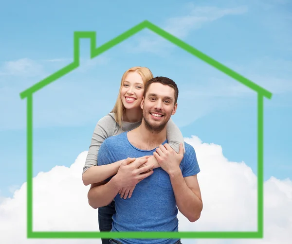 Sorridente coppia che abbraccia sopra casa verde — Foto Stock