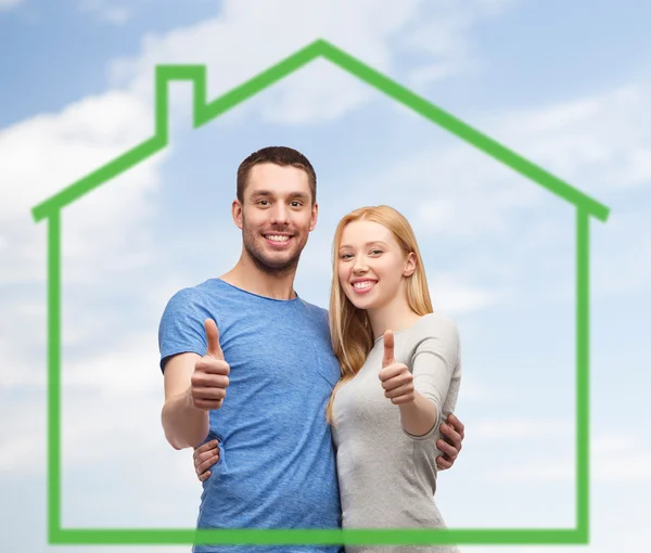 Sorrindo casal mostrando polegares para cima sobre casa verde — Fotografia de Stock