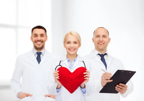 Group of smiling doctors with heart and clipboard — Stock Photo, Image