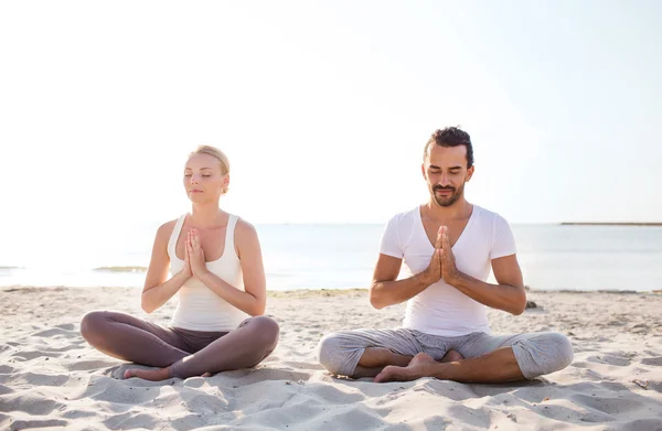 Sorrindo casal fazendo exercícios de ioga ao ar livre — Fotografia de Stock