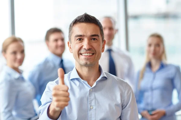 Sorrindo equipe de negócios mostrando polegares no escritório — Fotografia de Stock