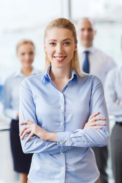 Glimlachende zakenvrouw met collega's in office — Stockfoto